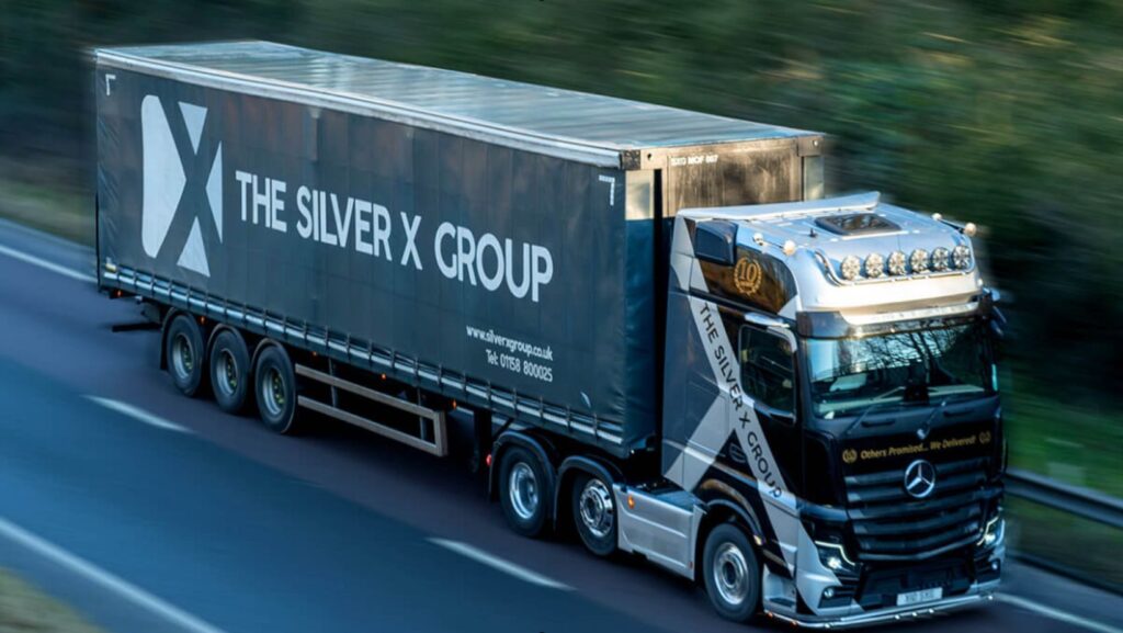 Silver X branded lorry driving on the road